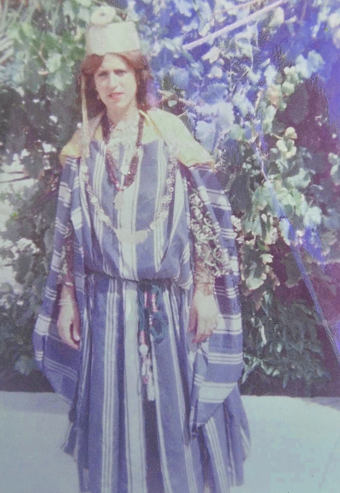 Archival portrait of a woman in traditional clothing among leafy plants, featured in the Photoalboom project